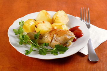 Roasted chicken leg with potatoes on dish