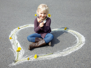 Naklejka premium Little girl sitting in a white heart playing with flowers