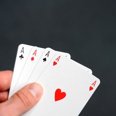 hand holding four aces