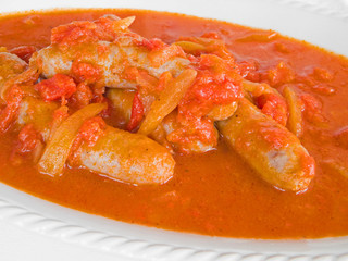 Sausages in tomato sauce on white dish.