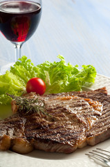 grilled porterhouse with salad and glass of wine