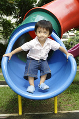 Fototapeta na wymiar Asian boy standing on a slide
