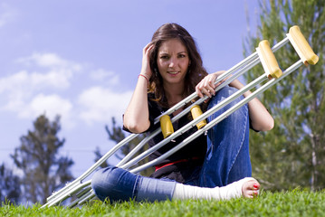 Woman seated with crutches outside