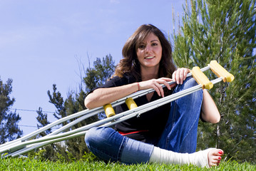 woman seated in park with crutches