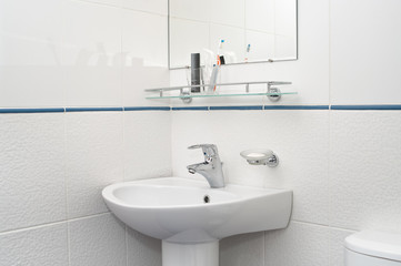 White bathroom with mirror and washbowl faucet and tooth brushes