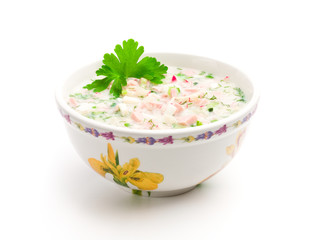 Bowl of cold soup with chopped vegetables, potherbs, meat and kv