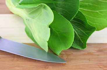 Baby bok choy vegetable and knife on cutting board