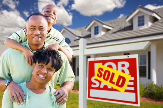 African American Family with Sold For Sale Sign and House