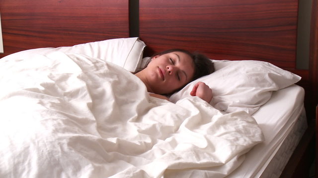 Relaxed brunette woman sleeping in her bedroom