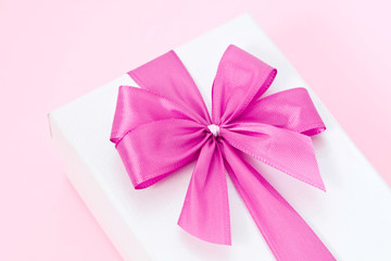 Paquet cadeau blanc avec noeud rose sur fond rose