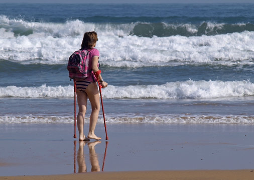 Mujer con muletas en la playa