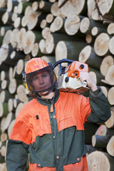 Waldarbeiter mit Kettensäge vor Buchenholz