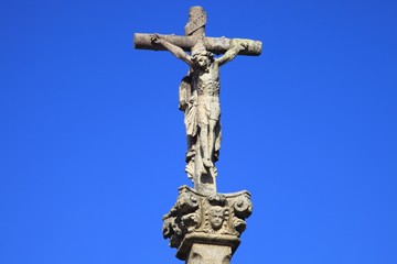 Jesus Christus am Kreuz, Steinfigur vor blauem Himmel