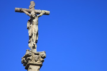 Jesus Christus am Kreuz, Steinfigur vor blauem Himmel
