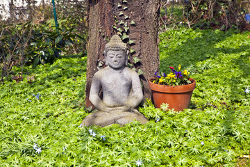 stone buddha in front of a cherry tree