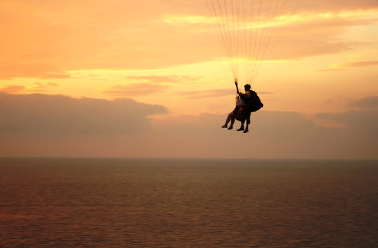 Flight of paraplane above Mediterranean sea on sunset