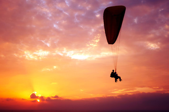 Flight of paraplane above Mediterranean sea on sunset