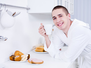 Smiling man with cup in the kitchen