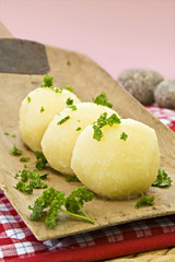 Kartoffelkl&ouml;&szlig;e serviert auf einem Holzbrett