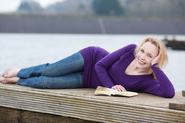 frau liest ein buch am see