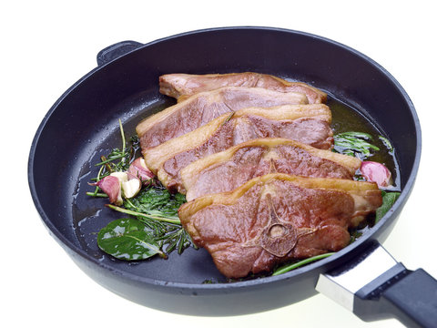 saddle of lamb, garlic & herbs roasting in a pan