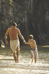 padre e foglio che corrono in spiaggia