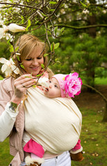 Beautiful young mother with her baby daughter in a garden at spr