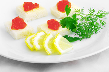 Sandwiches with red caviar and greens on a white plate