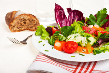 gemischter Salat auf einem weißen Teller mit einer Gabel