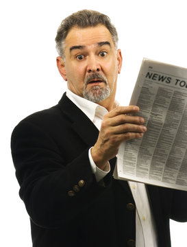Man looks shocked while reading newspaper