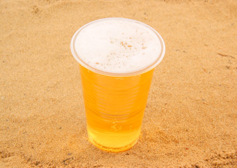Glass of fresh beer on desert sand