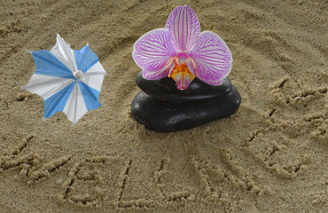 Fototapeta premium Steine mit Orchidee und Sonnenschirmchen auf Sand