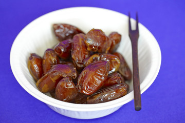 Bowl of date fruit with a wooden fork