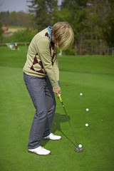 Fototapeta premium Woman golfer practicing putting on a green