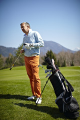 Man with a golf club and bag on the green