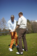 Golfer with a teacher practicing