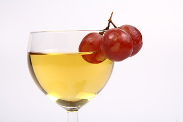 White wine in a wineglass with three red grapes