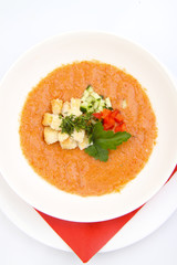 White bowl of tomato soup on white background