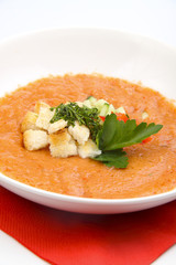 White bowl of tomato soup on white background