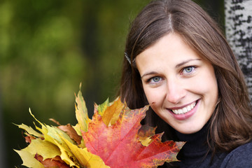 Beautiful romantic brunette with golden autumn leaf