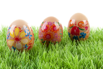 decorated chicken eggs in grass over white background