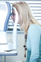 optometry concept - pretty young woman having her eyes examined