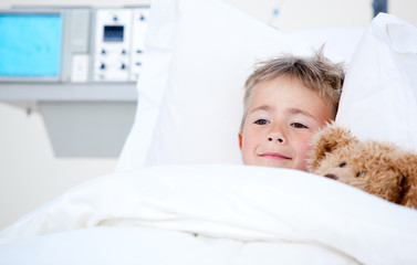 Sick cute little boy lying in a hospital bed
