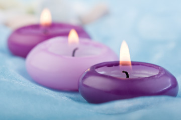 Obraz na płótnie Canvas purple toned candles on baby blue silk (2)