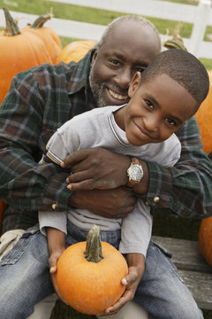 Portrait of African father and son holding pumpkin