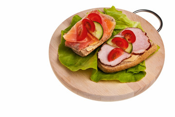 Two sandwiches with ham, smoked salmon and tomato.