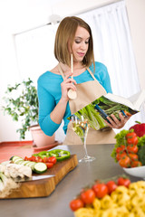 Obraz na płótnie Canvas Cooking - Woman reading cookbook in kitchen