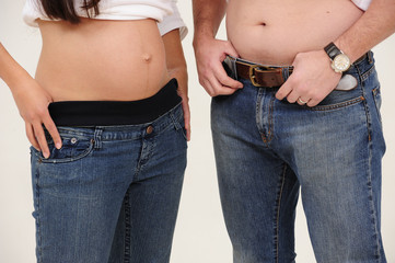 young pregnant couple standing with belly exposed