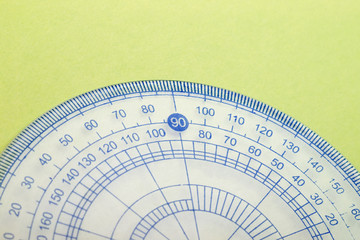 Closeup of transparent blue protractor on green paper texture