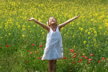 Pretty young girl happy to be surrounded by rapeseed flowers